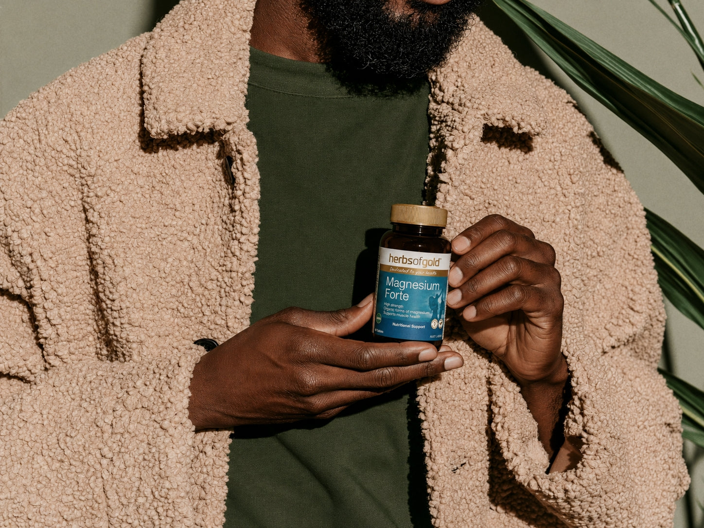 Person holding Herbs of Gold Magnesium Forte supplement bottle